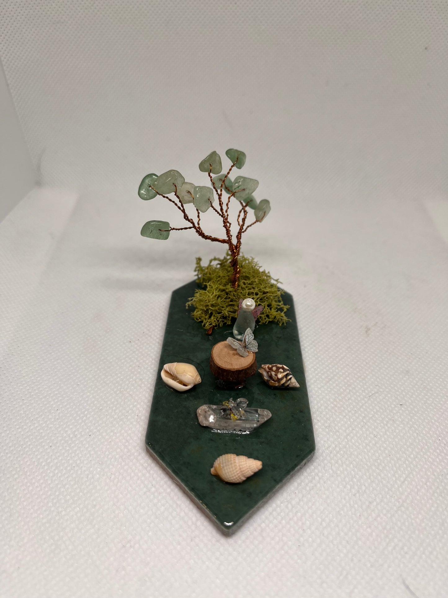 Small White Sea Glass Fairy Cottage Conch Shell w/ Wood Slice Table, Quartz Bench, and Aventurine Tree on Green Tile